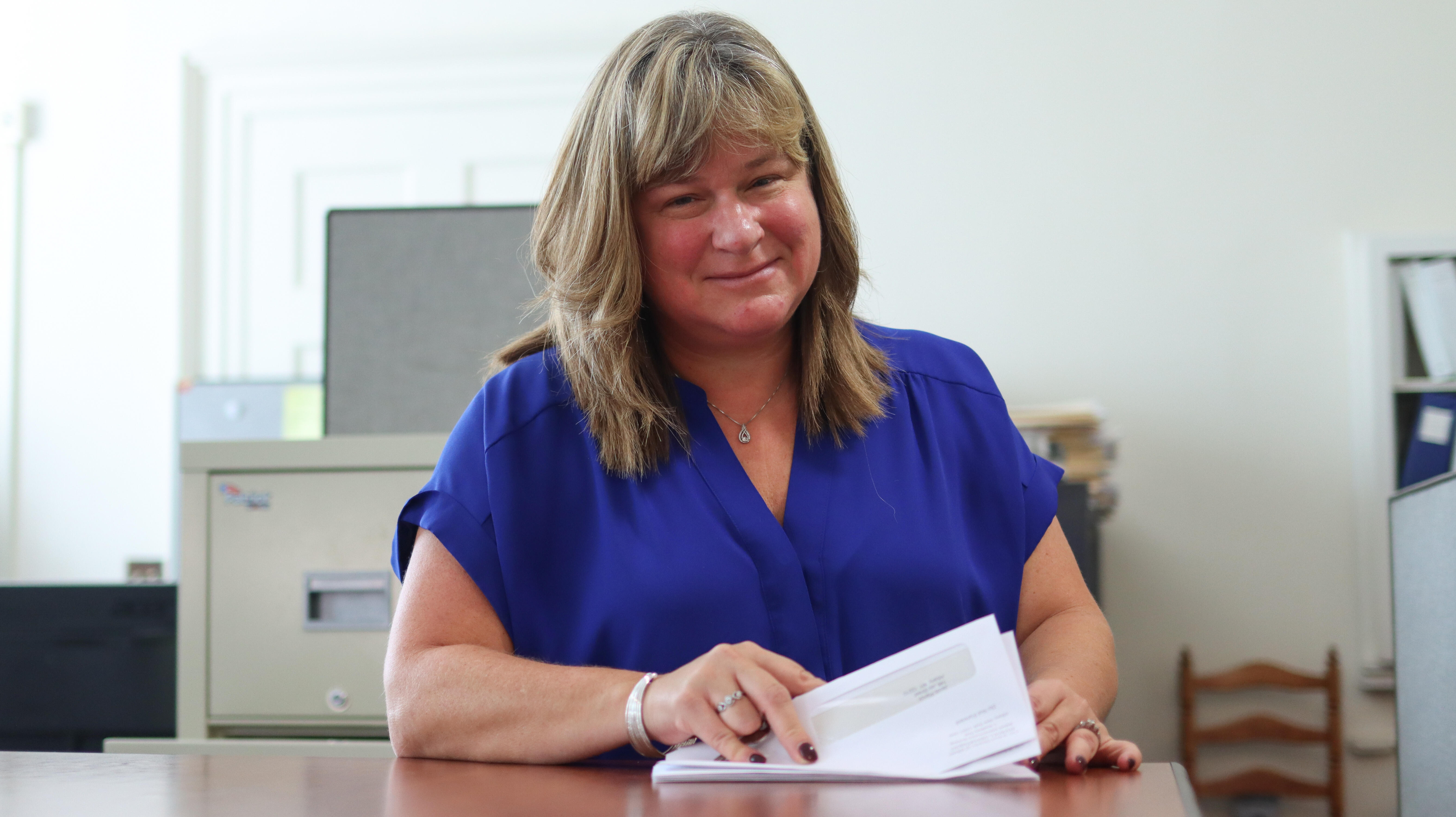 Business office employee smiling while sorting envelopes