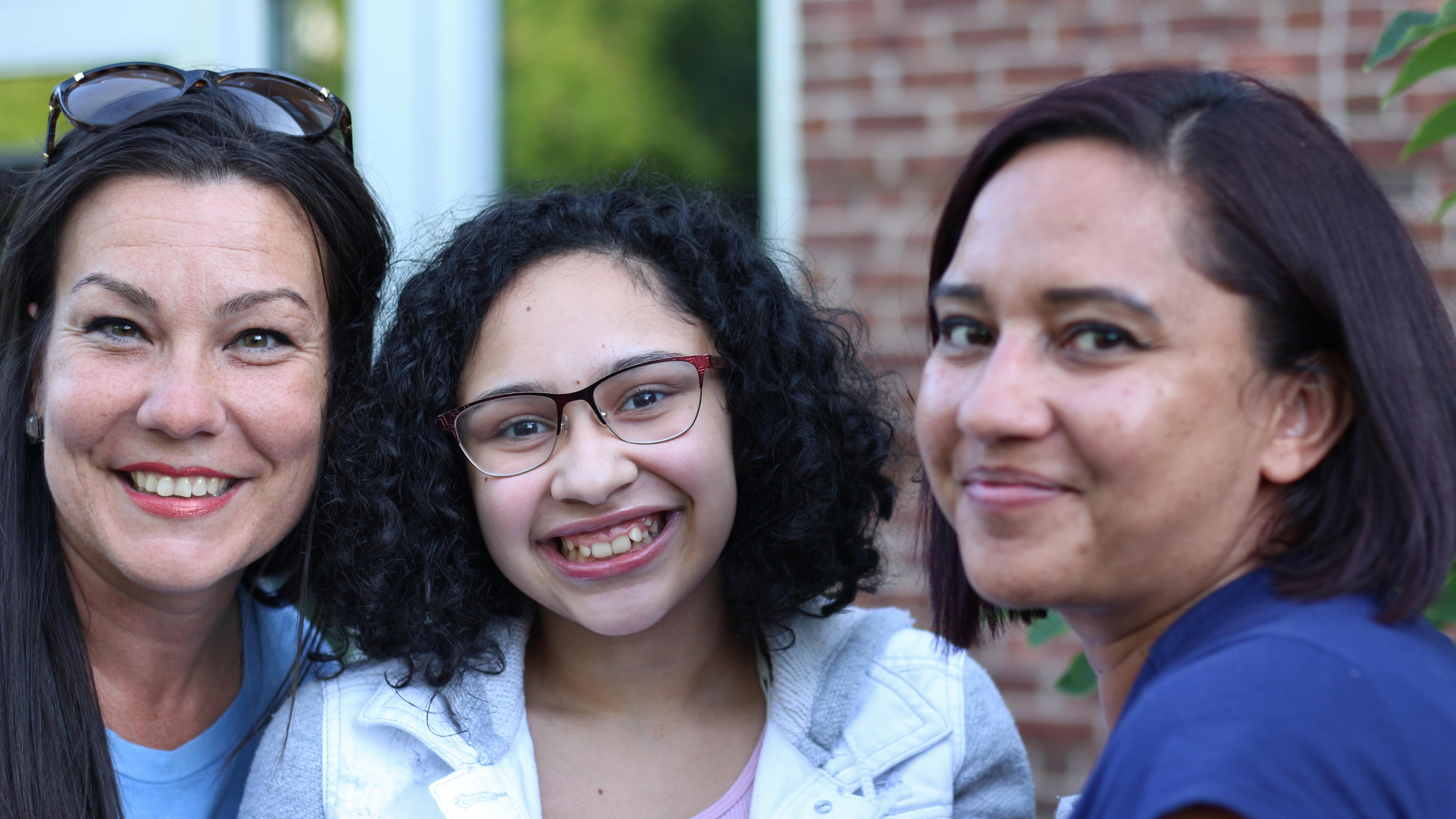 Female staff member smiling with a mother and daughter.