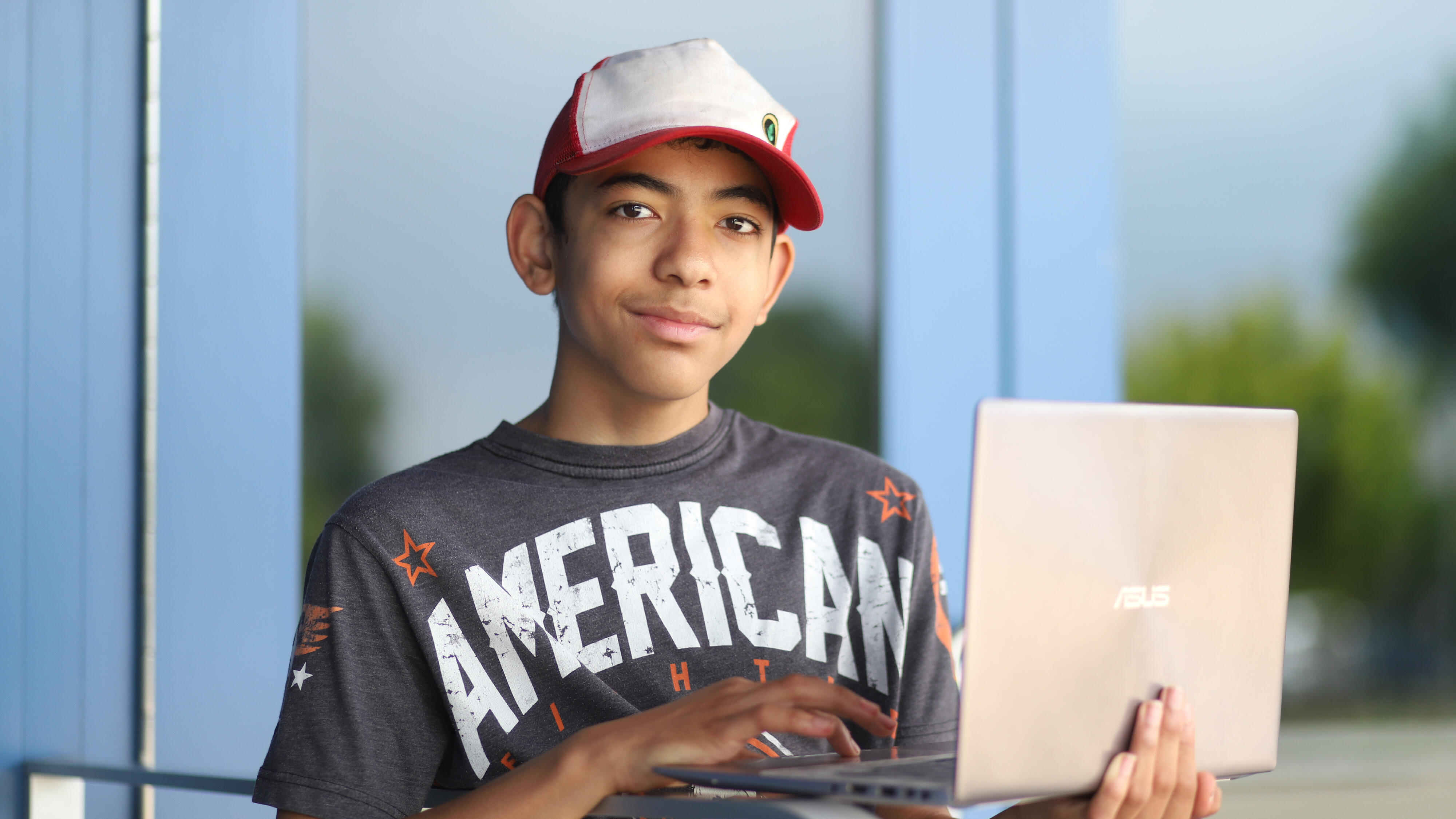 Student smiling while holding a laptop