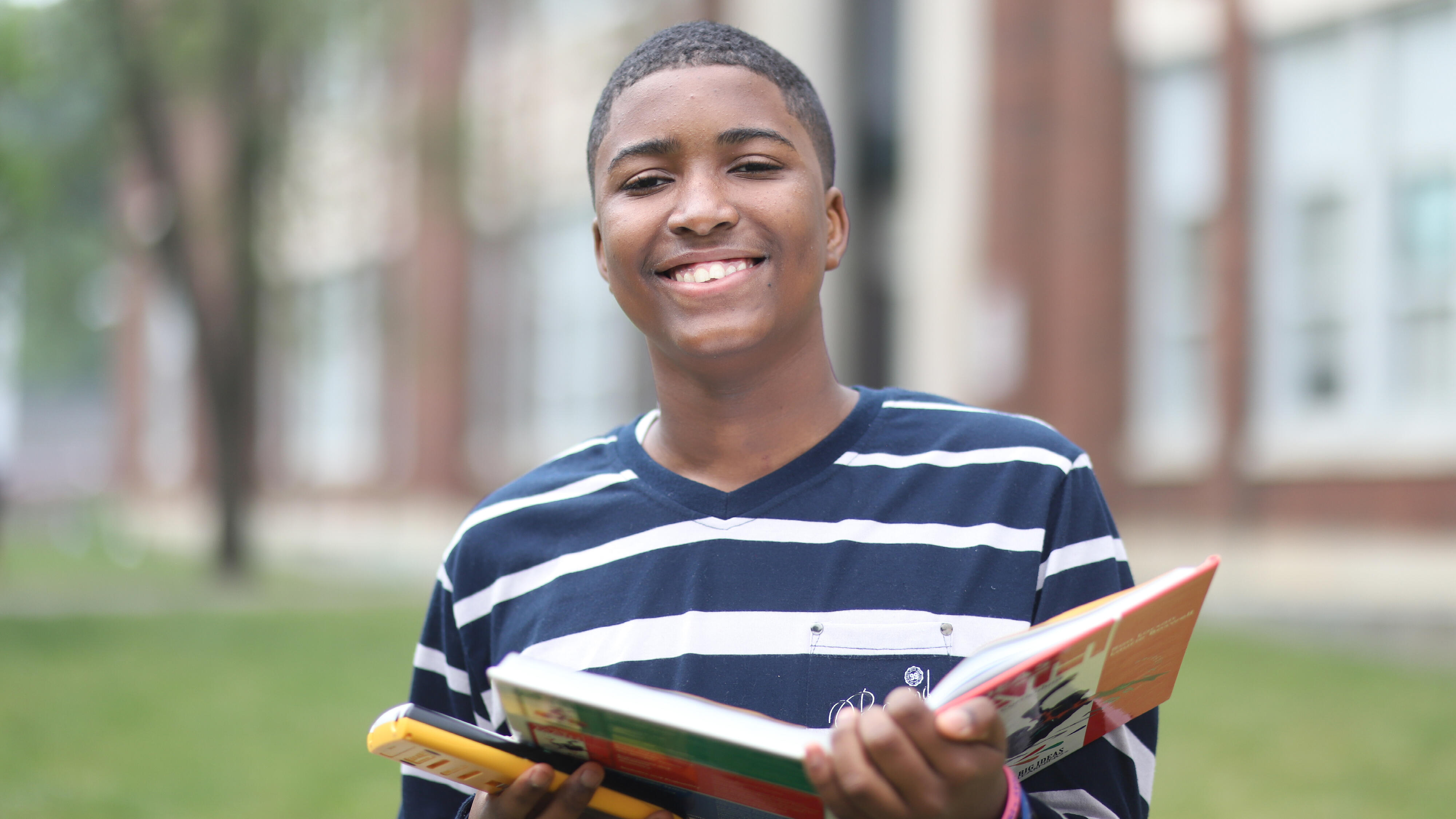 Student smiling while holding a math textbook and calculator